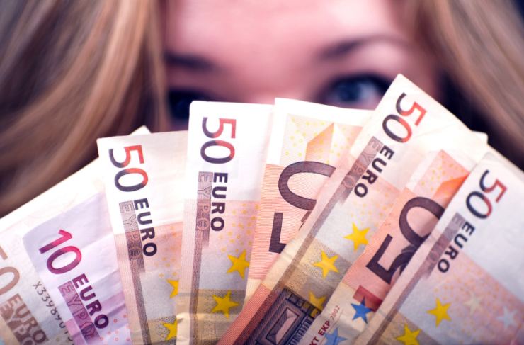 ragazza che si copre il viso con delle banconote di euro