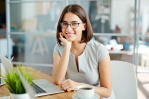 ragazza che sorride seduta alla scrivania davanti al computer