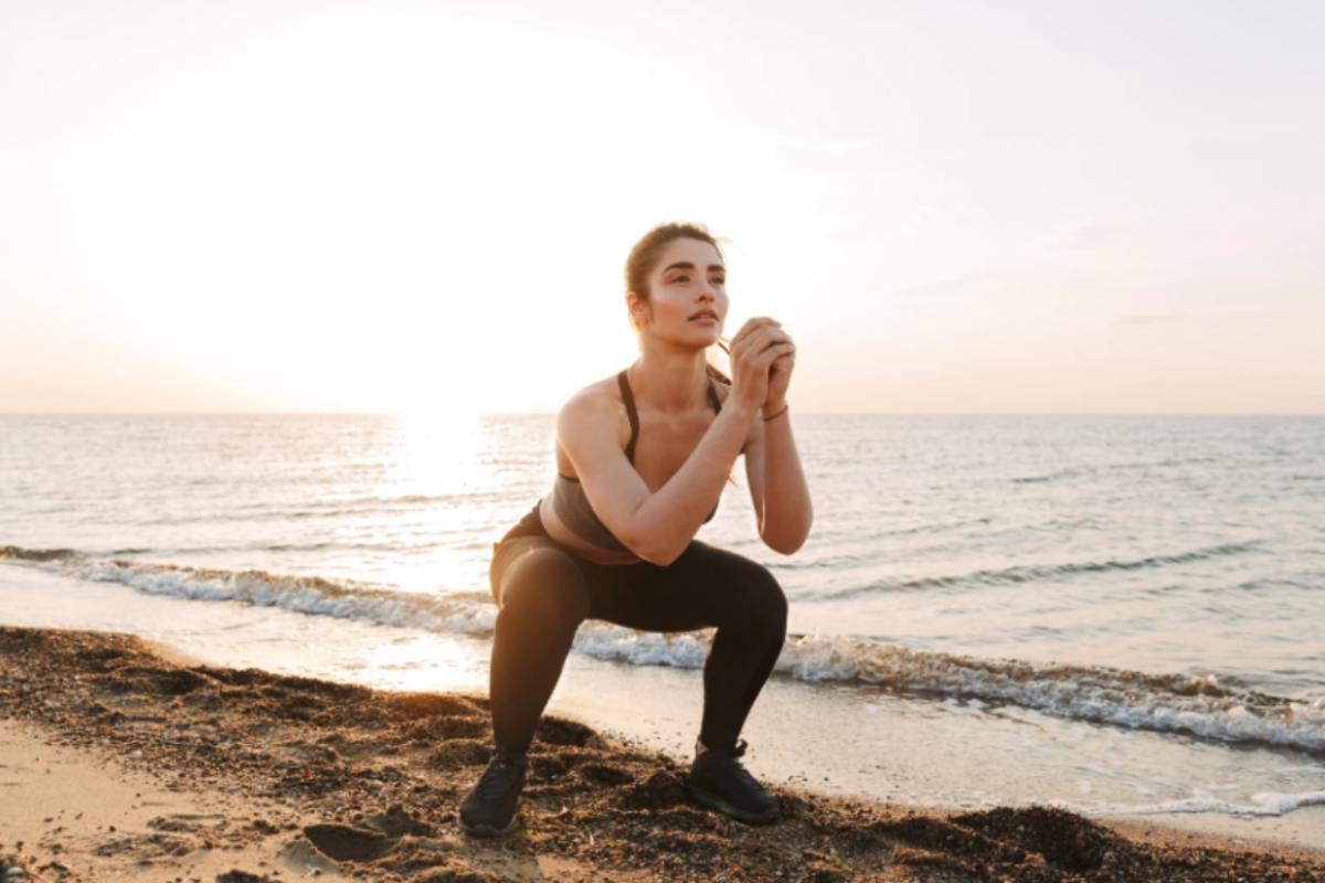 donna che fa squat in spiaggia
