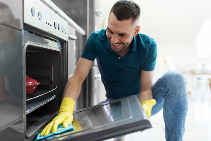 uomo che pulisce vetro del forno