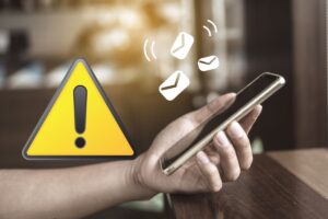 mano di una persona che tiene un cellulare in mano e riceve messaggi con un segnale di pericolo a sinistra