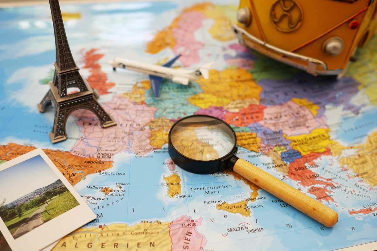 una cartina geografica con sopra una miniatura della torre eifel, una lente di ingrandimento una foto ed una miniatura di un aereo