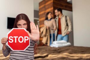 coppia che arriva nella stanza d'albergo e donna con cartello stop in mano