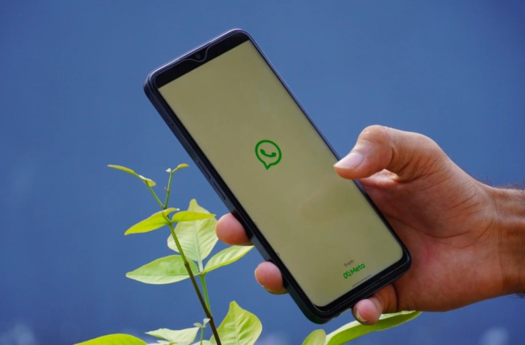 persona con in mano il cellulare e sullo schermo l'icona di whatsapp