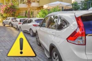 macchine parcheggiate sul marciapiede e il simbolo attenzione