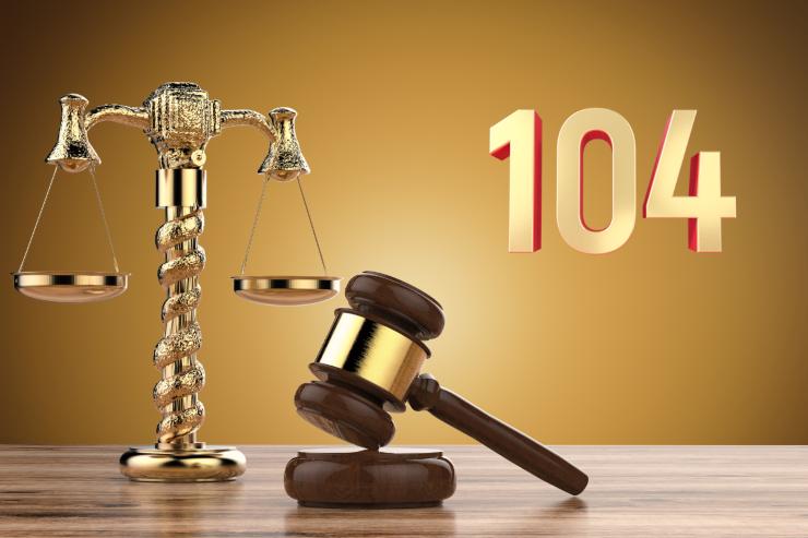 una bilancia e un martelletto della giustizia con in alto il numero 104