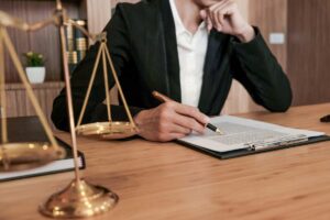 avvocato che scrive su un foglio ed in primo piano una bilancia come simbolo di giustizia
