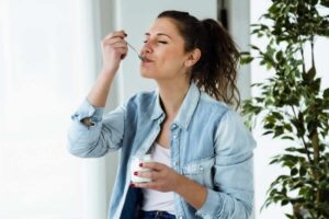 Ragazza con cucchiaino di yogurt in bocca