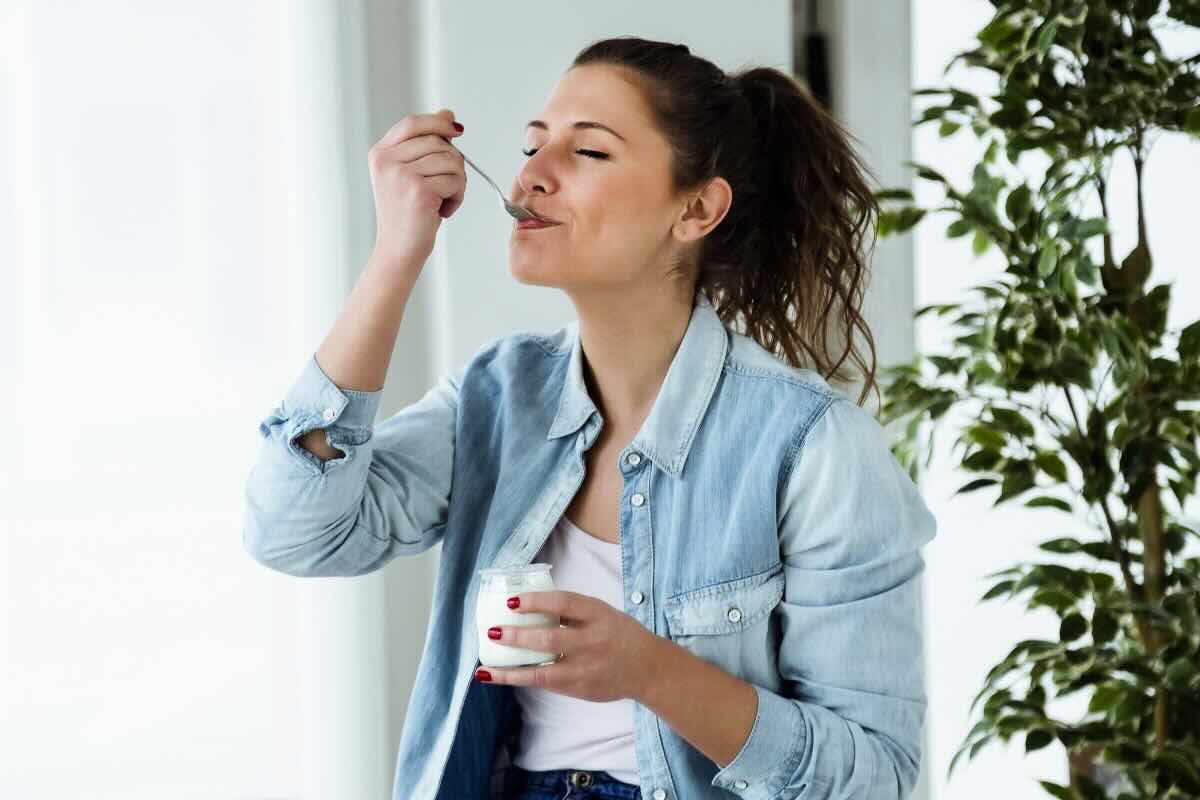 Ragazza con cucchiaino di yogurt in bocca