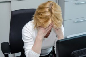 donna disperata con le mani sulla fronte seduta di fronte al computer