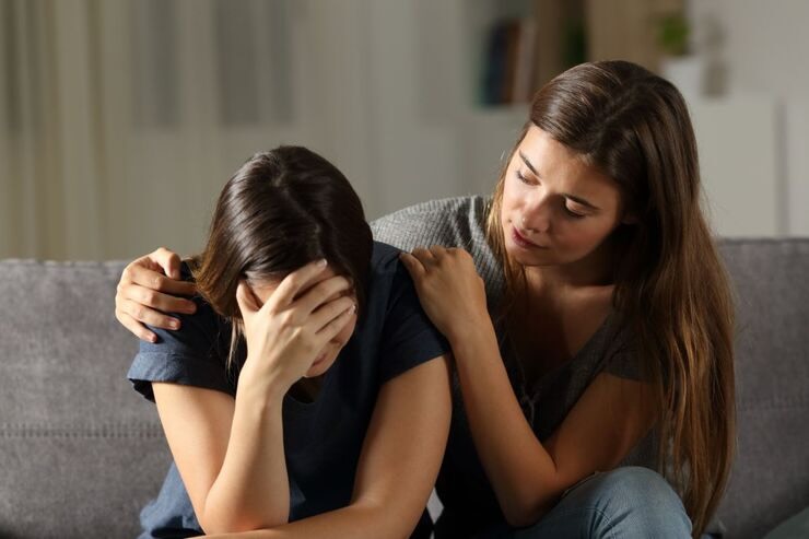 Donna consola ragazza triste con mano sul viso