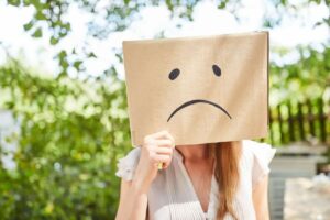 Ragazza con foglio sul viso con faccina triste