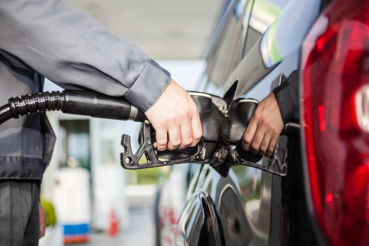 persona che sta facendo rifornimento per la sua auto.