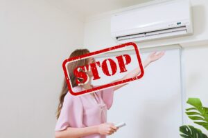 una persona che usufruisce del condizionatore fisso, in primo piano una scritta "STOP"