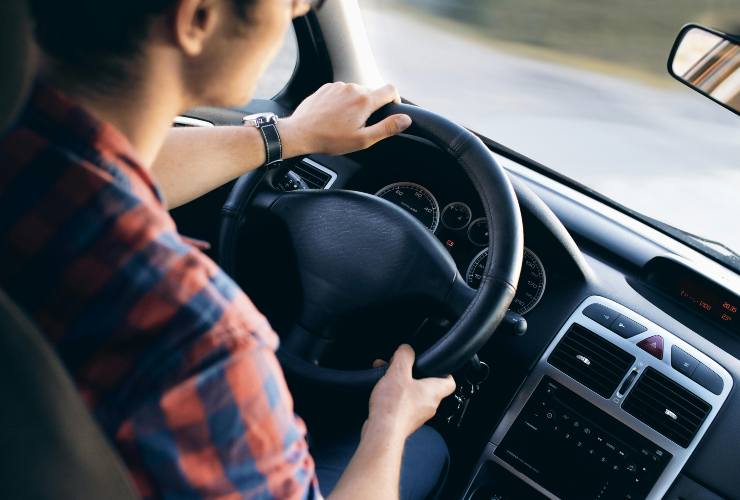 Mani di un ragazzo al volante dell'auto