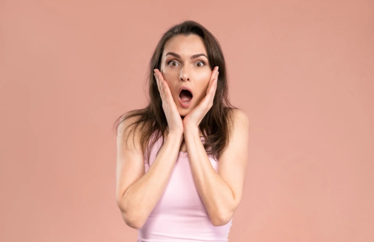donna scioccata con la bocca aperta e le mani in faccia