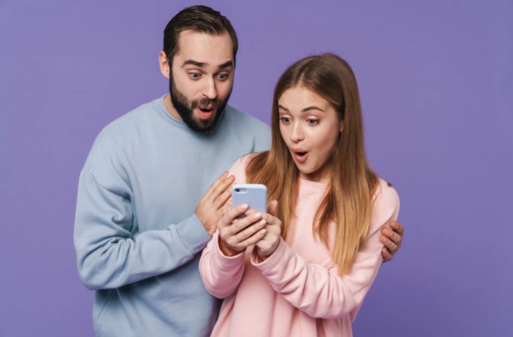 uomo e donna stupiti che guardano un cellulare